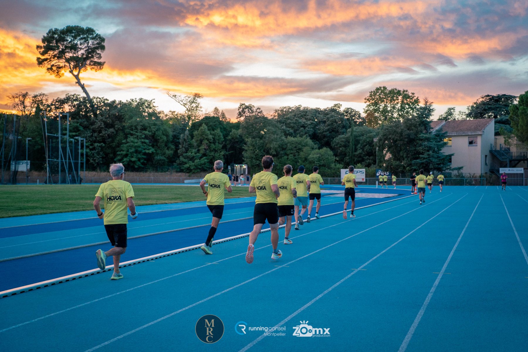Coureurs sur une piste d'athlétisme au coucher du soleil
