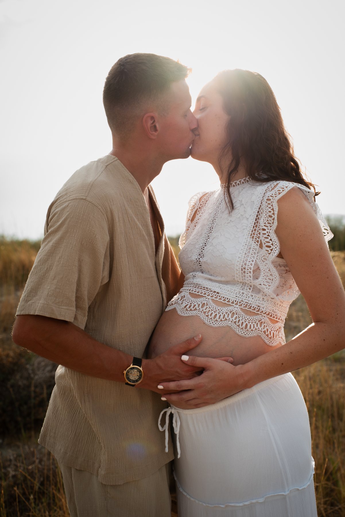 Le couple s'embrasse, les mains sur le ventre