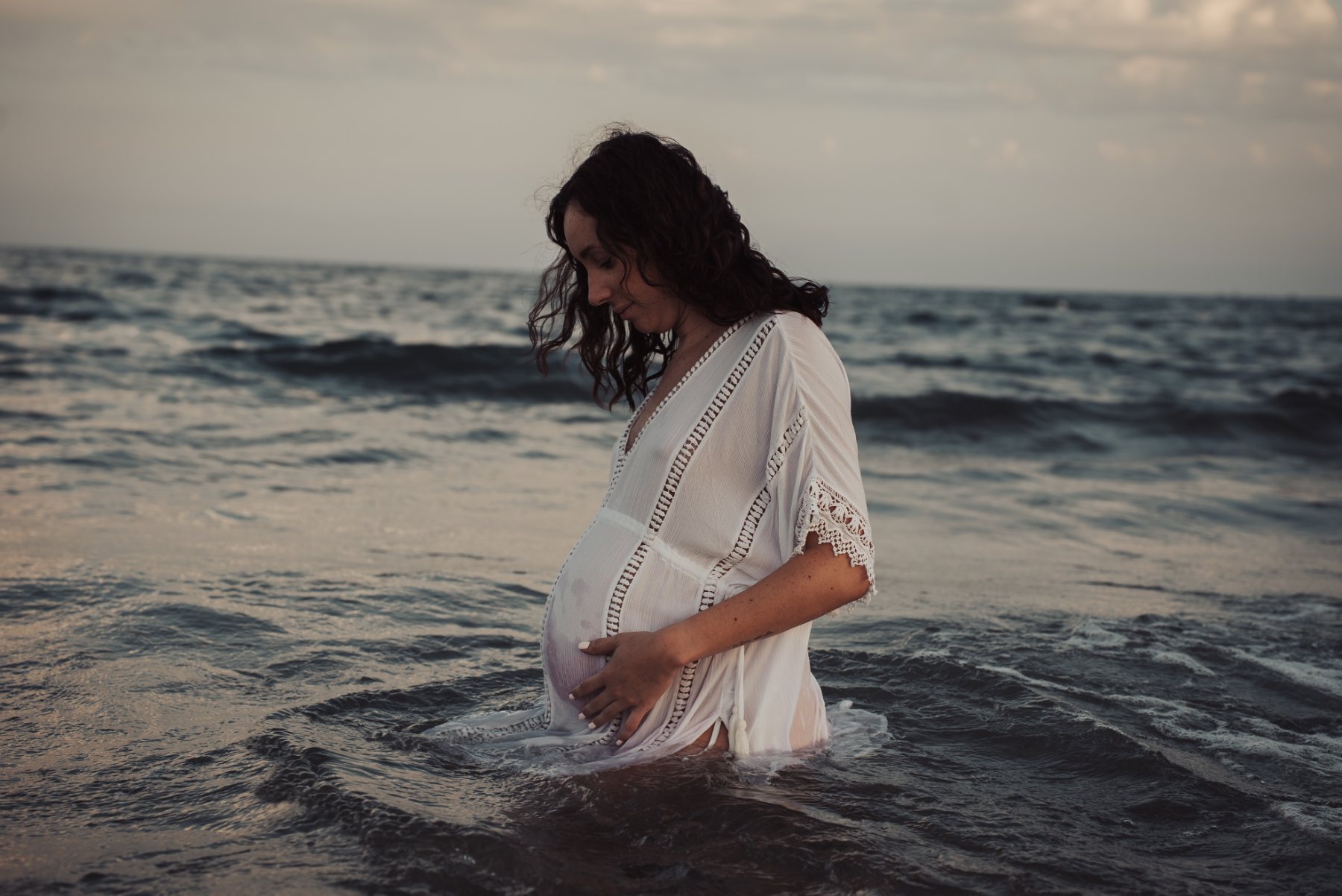 Future maman dans la mer au crépuscule